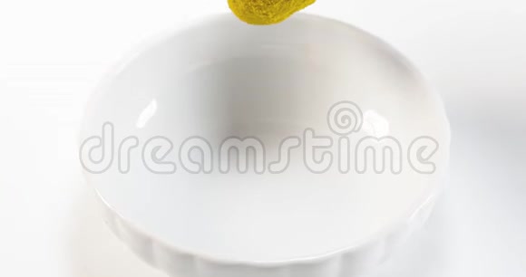 咖喱粉在白色背景下掉进碗里视频的预览图