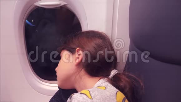 航空飞机概念坐在窗边的小女孩睡在飞机上夜间飞行的生活方式视频的预览图