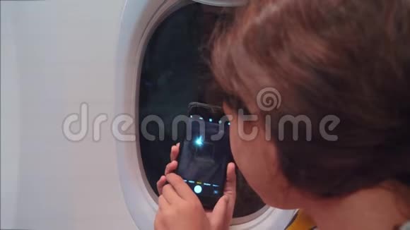 航空飞机概念年轻女孩正坐飞机在下面的智能手机夜城拍照视频的预览图