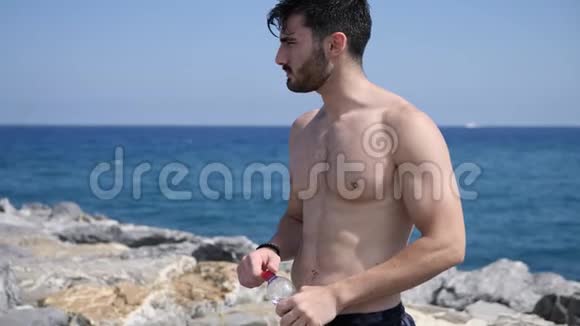 可爱的赤膊肌肉男在海滩上喝水视频的预览图