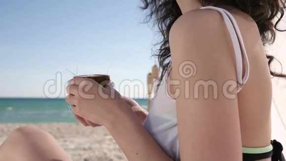 带卷发的微笑女孩在海滩上女人喝鸡尾酒异国情调夏季背景海洋和海洋视频的预览图