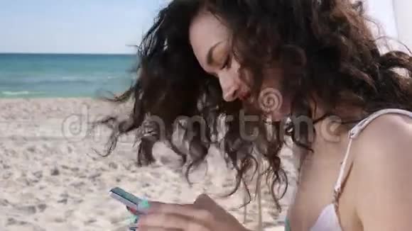 女孩在海滩上的社交网络中交谈微笑的女人在海洋海岸使用手机年轻的女人在手机上查看资料视频的预览图