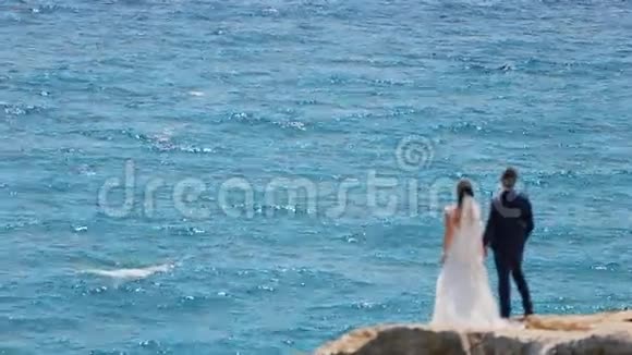 新娘在岩石上眺望大海视频的预览图