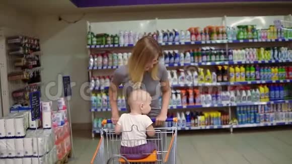 小宝宝和她妈妈在超市玩得很开心可爱的孩子坐在购物车里而她的母亲却在视频的预览图