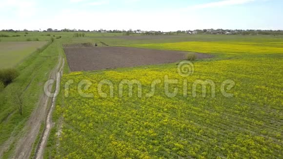 接近拖拉机耕种耕地播种作物黄菜籽空中景观视频的预览图