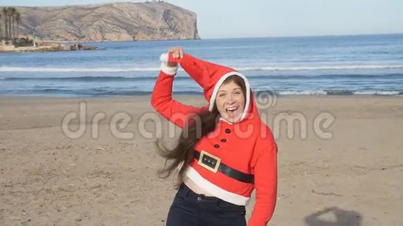 穿着圣诞帽跳舞和在海滩上玩得开心的漂亮年轻女子视频的预览图