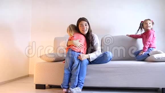 年轻的母亲和两个女儿在客厅的沙发上玩耍视频的预览图