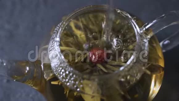 茶叶酿造干茶叶用开水淹没绿茶叶在玻璃壶中旋转视频的预览图