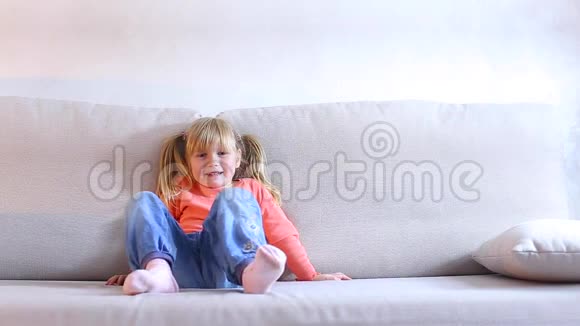 欧洲的小女孩看起来坐在沙发上在照片相机上摆姿势视频的预览图