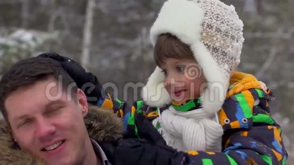 快乐父亲的肖像和一个非常可爱的快乐小男孩他的儿子在一个雪冬公园微笑的男孩有吸引力的家庭视频的预览图
