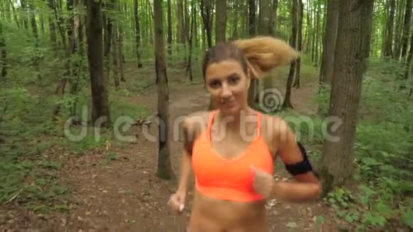 一位黑发的运动女子长发在森林跑道上奔跑视频的预览图