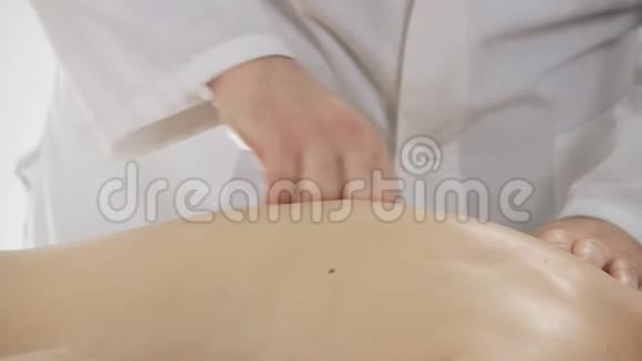 在按摩沙龙里按摩师按摩一个年轻女孩的背部特写视频的预览图