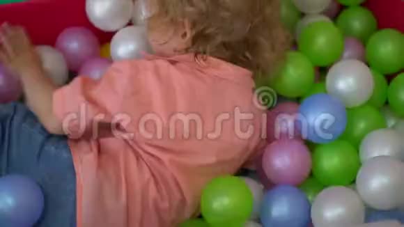 快乐的孩子在多种颜色的球池里玩托儿所视频的预览图