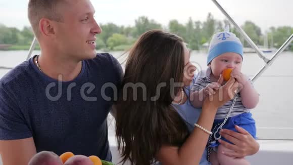 父母带着孩子在游艇上孩子吃第一餐在手上妈妈休息爱夫妻和小宝宝在一起视频的预览图