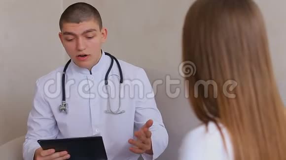 成熟的女人来看医生听和写一男一女坐在后台沙发上的医疗办公室视频的预览图