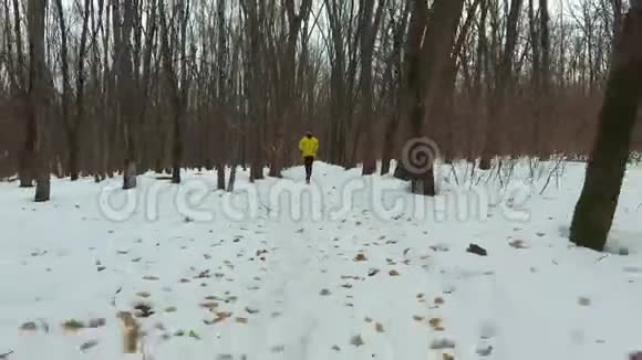 冬季寒冷的一天在森林中进行黄色外套训练的小胡子跑步者视频的预览图
