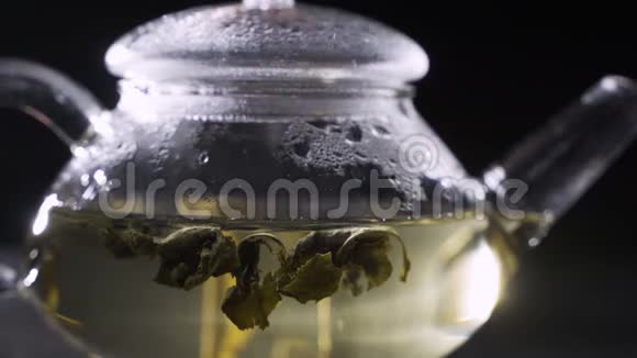 茶叶酿造干茶叶用开水淹没绿茶叶在玻璃壶中旋转视频的预览图