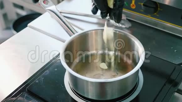 厨师手戴手套将切碎的大蒜放入锅中视频的预览图