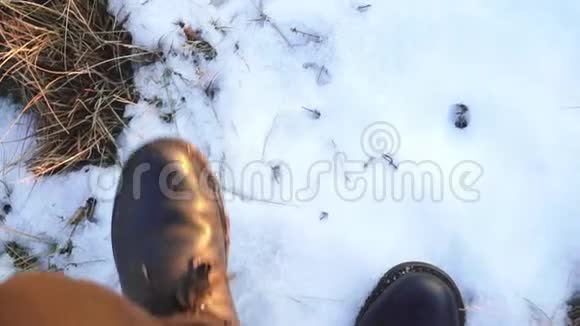 一个穿着黑色靴子在夕阳下的雪地里行走的人的腿视频的预览图