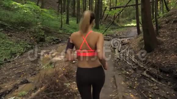 长头发的女运动员在森林跑道上奔跑运动和娱乐视频的预览图