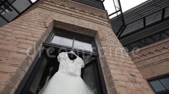 白色婚纱挂在阳台的光圈窗口和砖块场景中视频的预览图