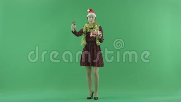 一位年轻女子正在用她的圣诞礼物在绿色屏幕上自拍视频的预览图