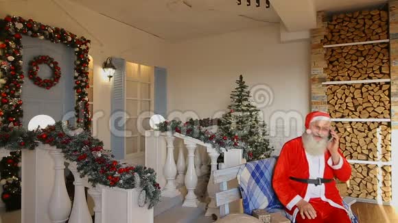圣诞爷爷打电话坐在装饰庭院的长凳上视频的预览图