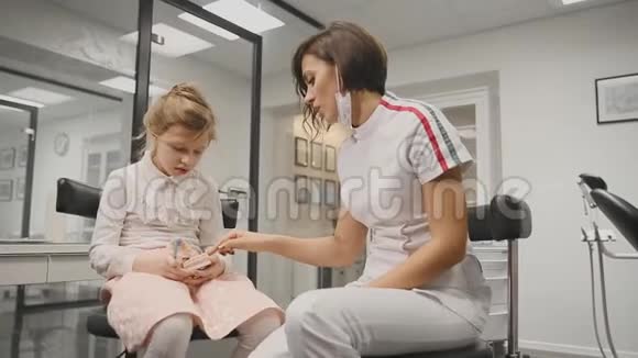 牙医告诉女孩如何刷牙显示布局为正确刷牙对准摄像机放大摄像机视频的预览图
