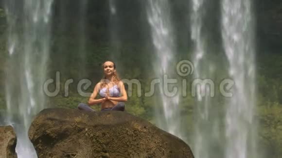 女人坐在石头上的莲花筒里对水视频的预览图