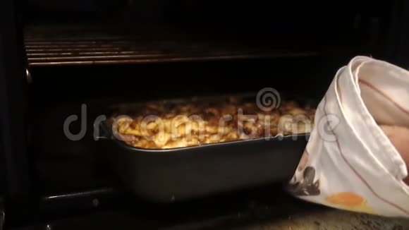 一个男人从烤箱里拿出烤土豆和肉视频的预览图