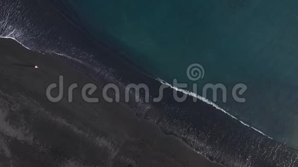 鸟瞰一个女孩走在海滩与黑色沙子海岸的大西洋西班牙加那利群岛特内里费视频的预览图