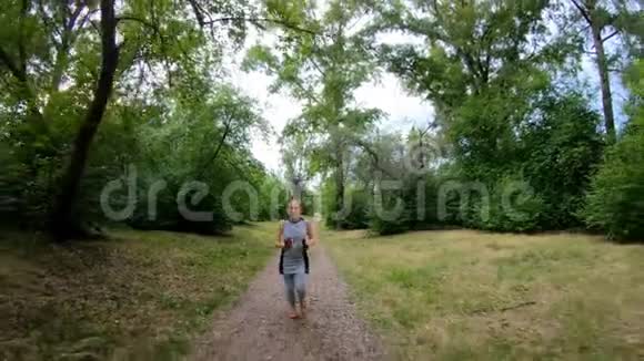 在公园里慢跑女孩沿着森林小径奔跑慢动作视频的预览图