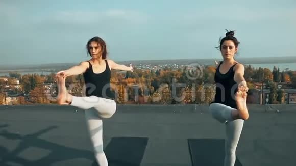 两位美女在屋顶上练习瑜伽早上在户外视频的预览图
