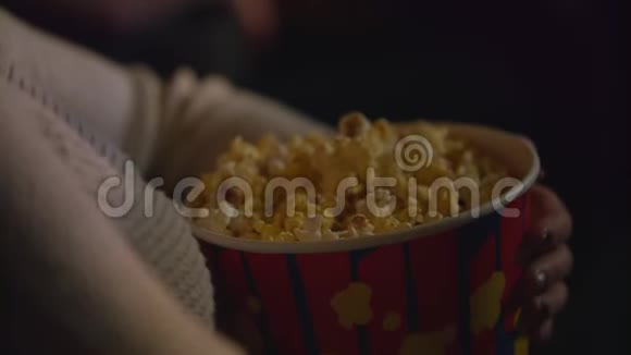 女用手从纸容器里拿爆米花在电影院吃爆米花视频的预览图