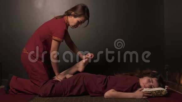 一位年轻女性和服女按摩师在水疗中心做泰式按摩的特写镜头泰国的按摩师正在伸展视频的预览图