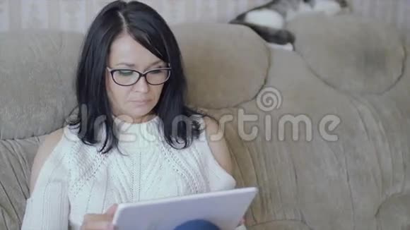 一个女人坐在沙发上手里拿着一块平板电脑视频的预览图