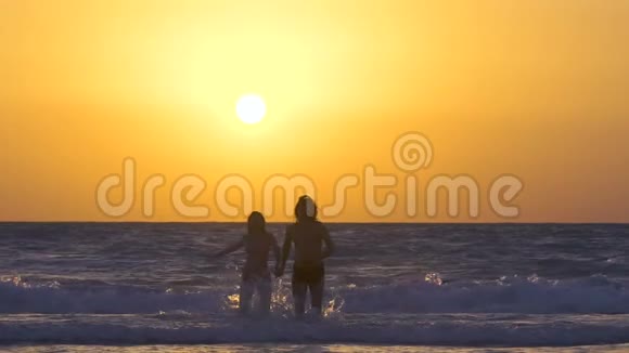 一对夫妇在日落时在海滩上奔跑和享受幸福的男人和女人牵着手在海边奔跑视频的预览图