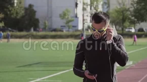 主题体育与健康一个年轻的白人男子使用智能手机smarfton听耳机音乐技术视频的预览图