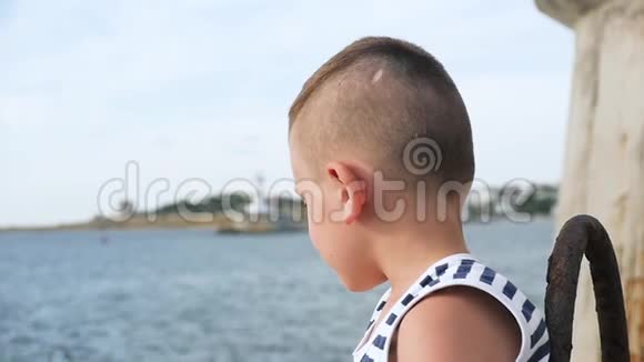 天空和大海背景上穿着水手条纹衬衫的会说话的小男孩视频的预览图