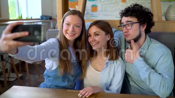 三个朋友坐在咖啡馆里玩得开心交流自拍慢动作视频的预览图