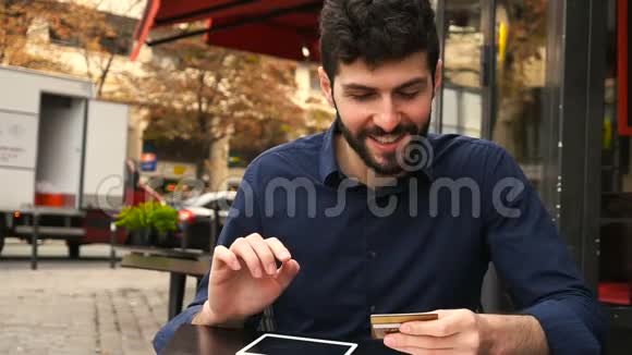 年轻的父亲在咖啡店用智能手机在线购买卡片动作缓慢视频的预览图