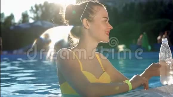 漂亮的健康女人游泳池里有一瓶水视频的预览图