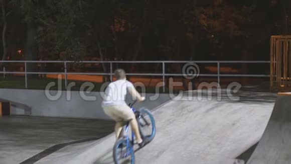 MTB自行车骑手在溜冰场骑自行车时做各种花样极限运动骑手在夜间表演桌面魔术视频的预览图