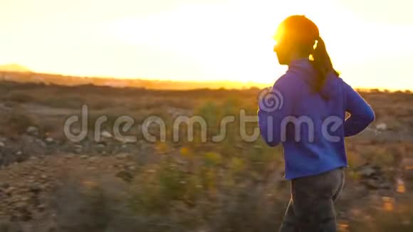 日落时分女人沿着荒芜的沥青路奔跑后景背景上的山脉慢动作视频的预览图