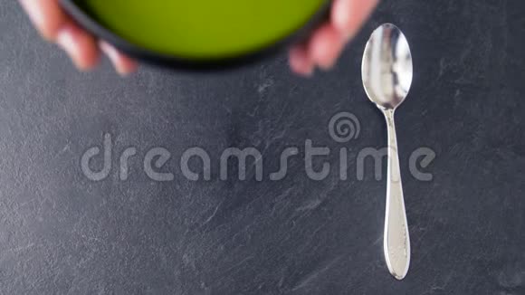 手把碗绿奶油汤放在桌上视频的预览图