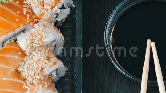 摄像机向右移动在酱油和中国竹签旁边的黑色木制背景上摆放时尚寿司视频的预览图