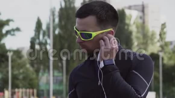 主题体育与健康一个年轻的白人男子使用智能手机smarfton听耳机音乐技术视频的预览图