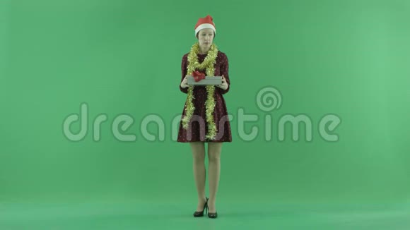 一位年轻女子正在绿色屏幕上打开圣诞礼物视频的预览图