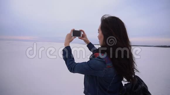 慢动作旅行者女孩用智能手机制作日落照片视频的预览图
