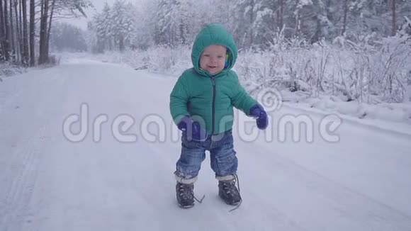 小男孩在在雪地上玩耍小男孩走在冬林里慢动作视频的预览图